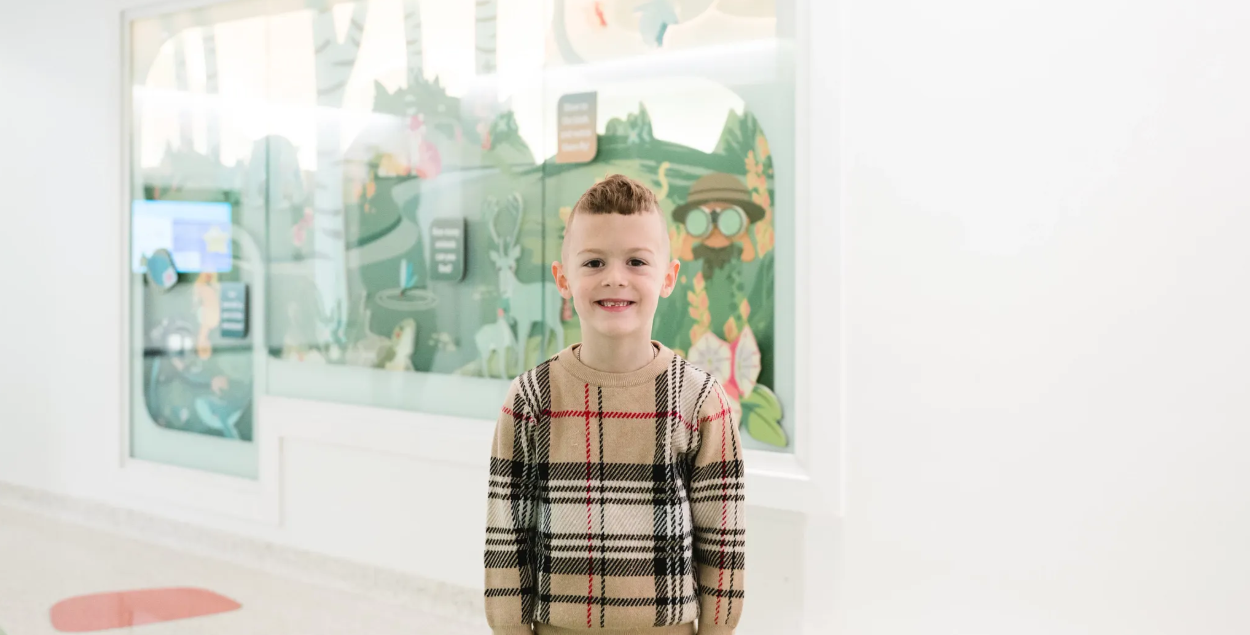 Junior smiles in front of the wayfinding wall