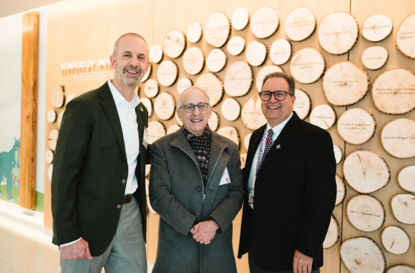 Guests smiling in front of donor wall in new Tower