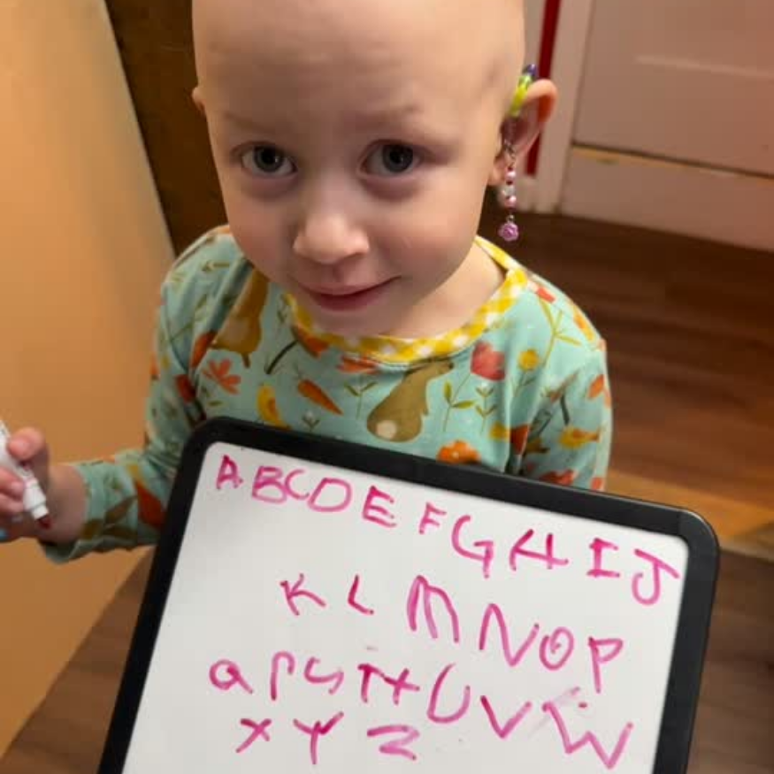 Anastasia writing the alphabet on a whiteboard