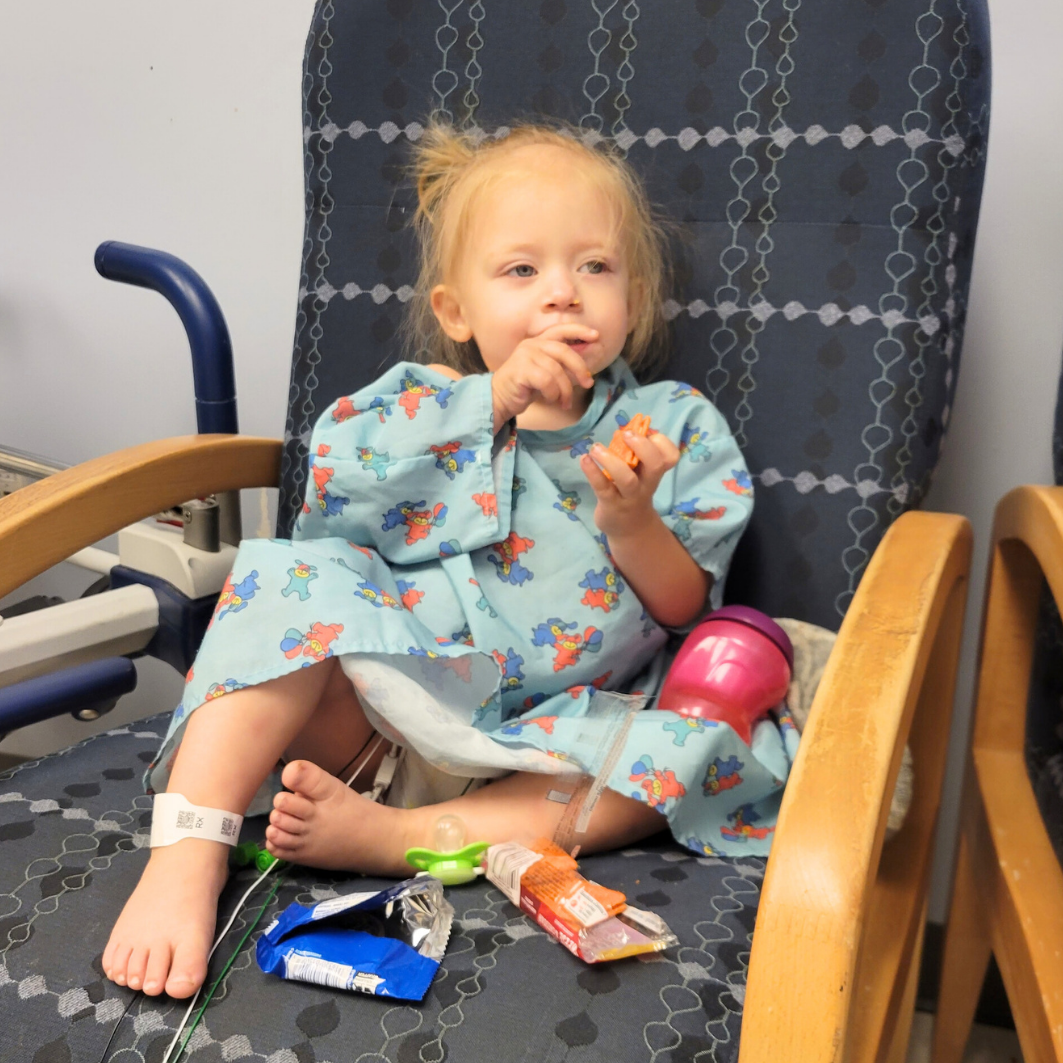 Anastasia sitting in her hospital gown eating snacks