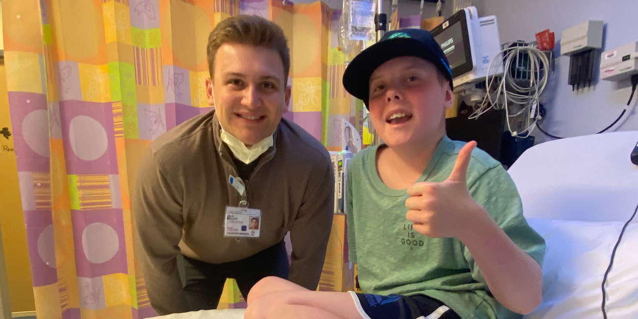 William giving a thumbs up in his hospital bed with care team member