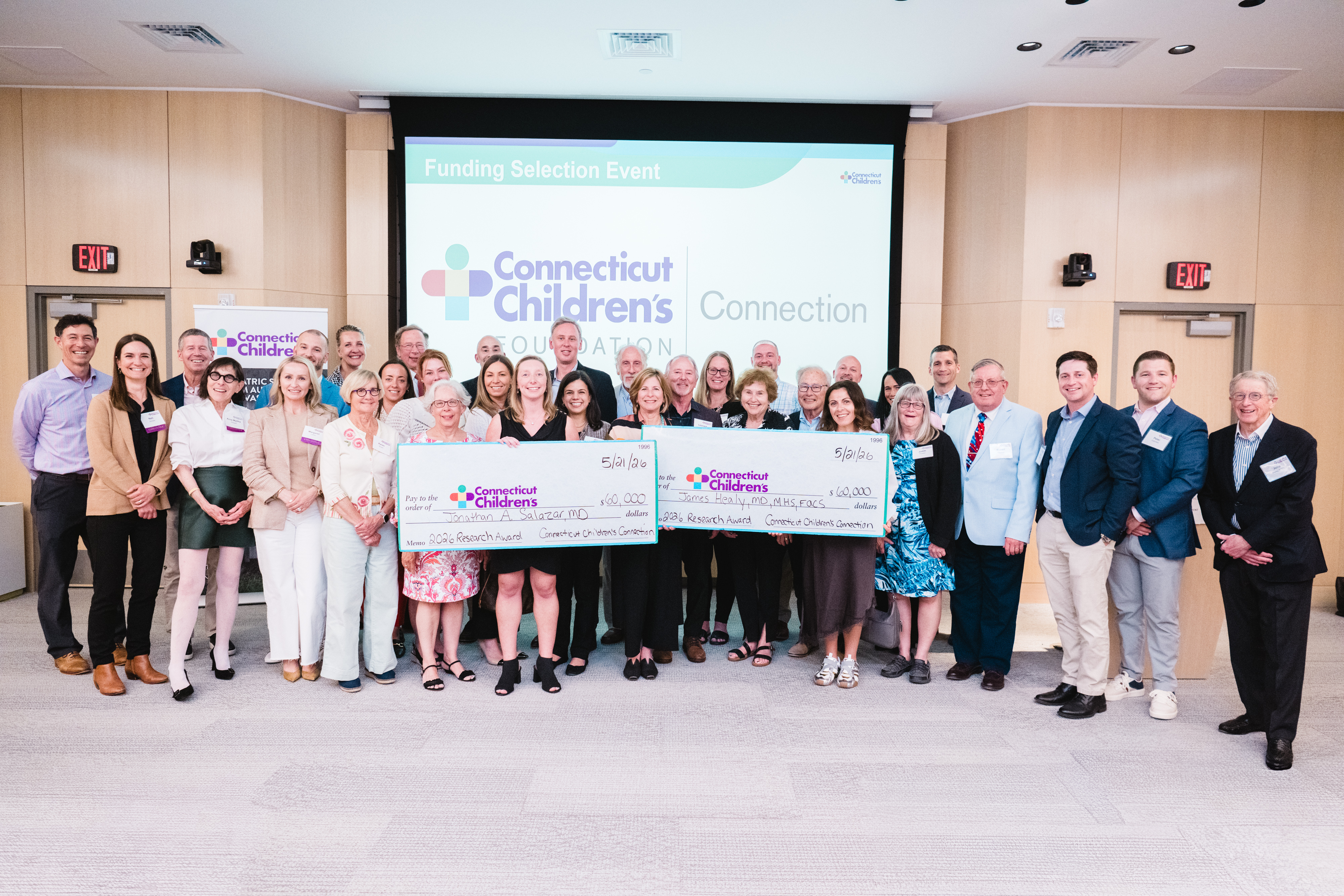 Connecticut Children's Connection members present two oversized checks, each for $60,000, as research grant awards.