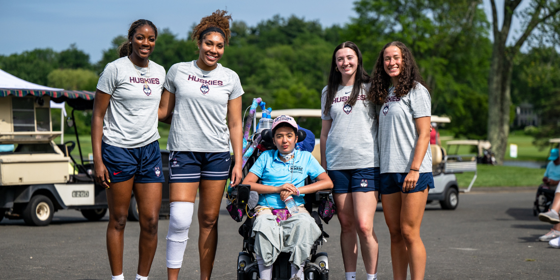 Patient Ella smiles with UConn WBB team