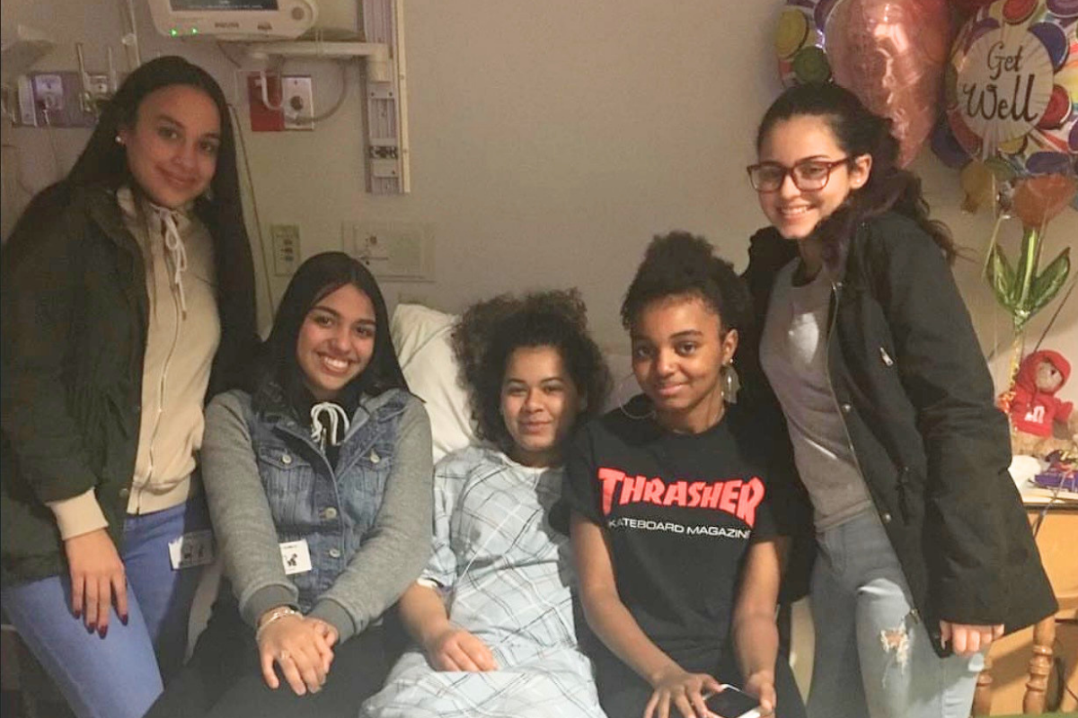 Evelyn smiling with her friends in hospital bed