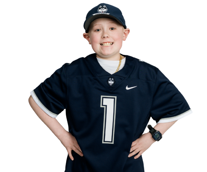 A pre-teen boy wearing a UConn football jersey and ballcap