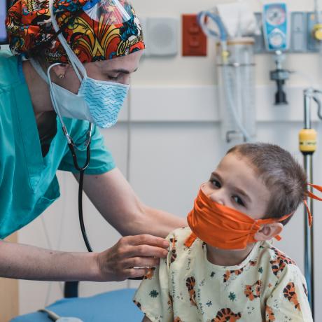 Nurse listens to masked chid's lungs