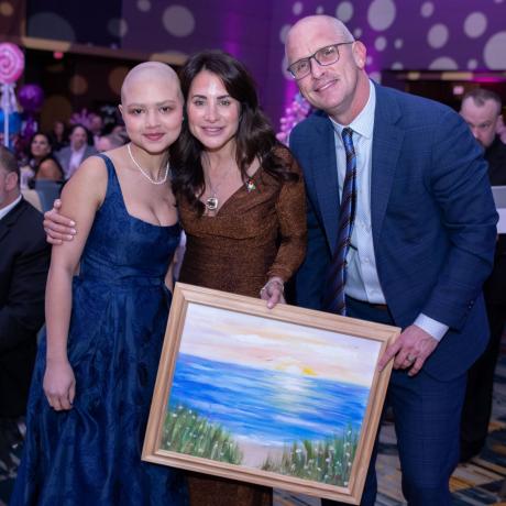 Dan and Andrea Hurley hold their newly won piece or art alongside artist and patient, Ava, who is battling cancer at Connecticut Children's..
