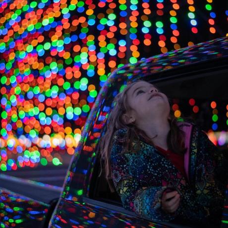 A young girl gazes up at the magical holiday light display.