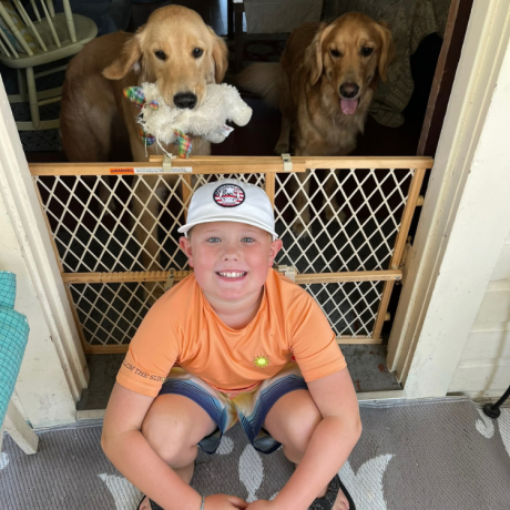 Carson smiling with his golden retriever dogs