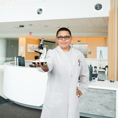 Elijah in a lab coat holding a microscope in the new tower