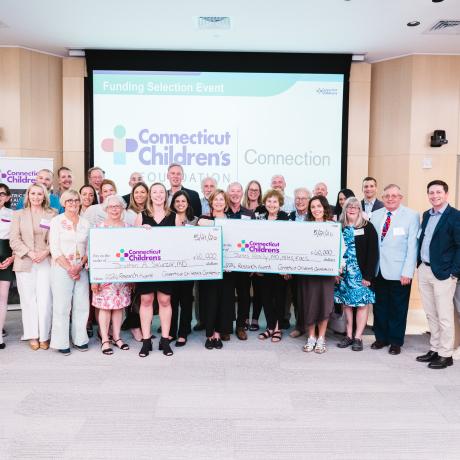 Connecticut Children's Connection members present two oversized checks, each for $60,000, as research grant awards.