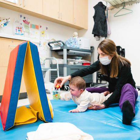 Patient using toy to crawl with care provider