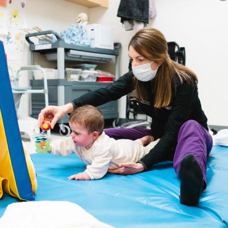 Patient using toy to crawl with care provider
