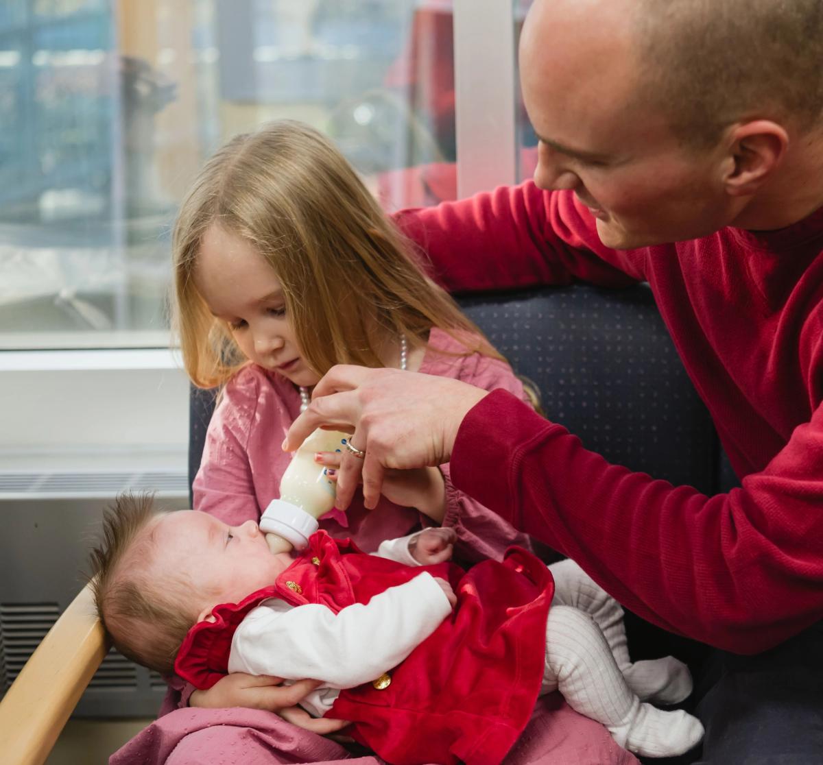 Elisabeth being held by her big sister and father