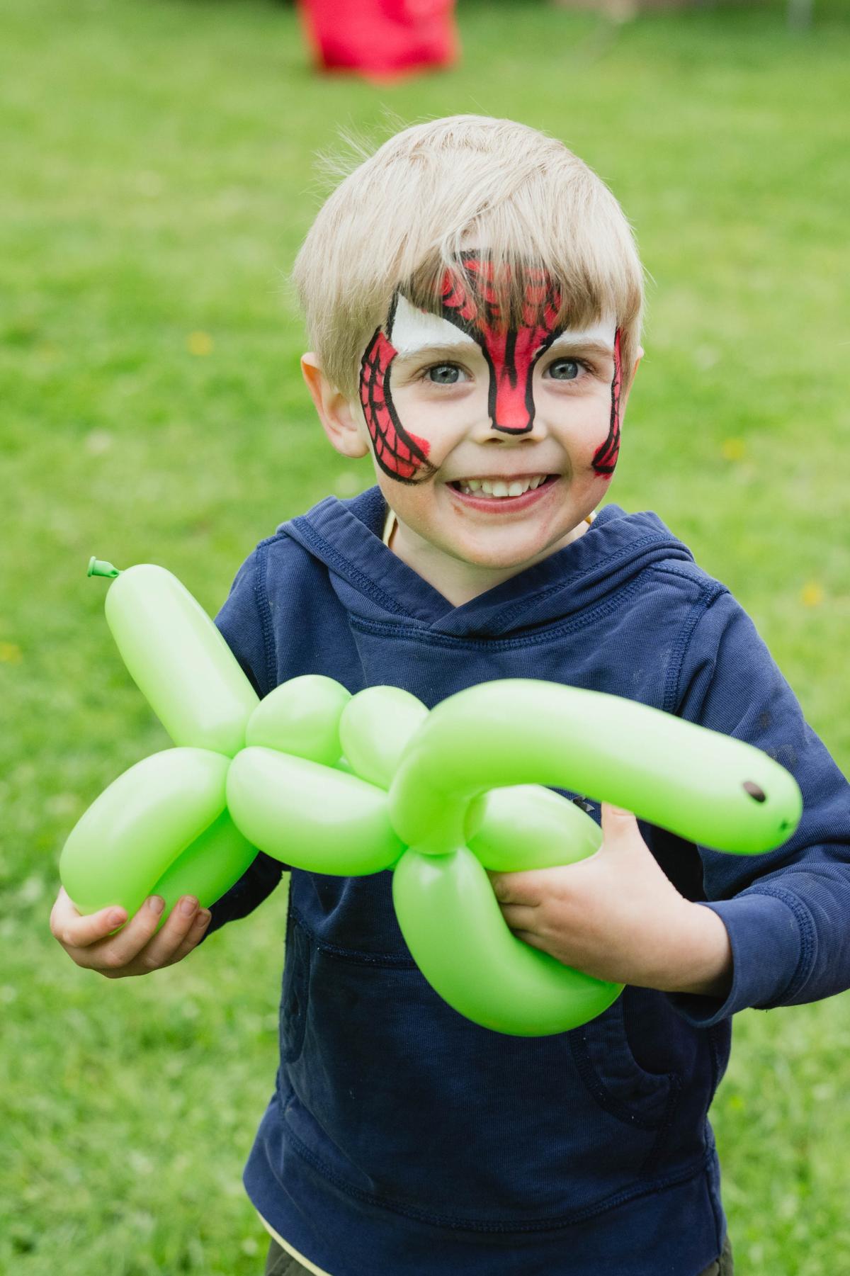 Child with spiderman face paint and a balloon animal