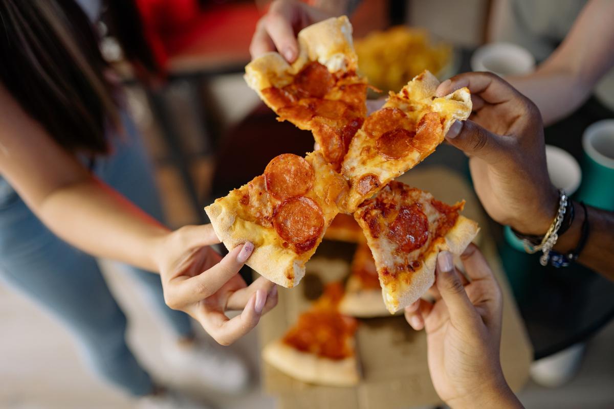 Individuals holding slices of pizza