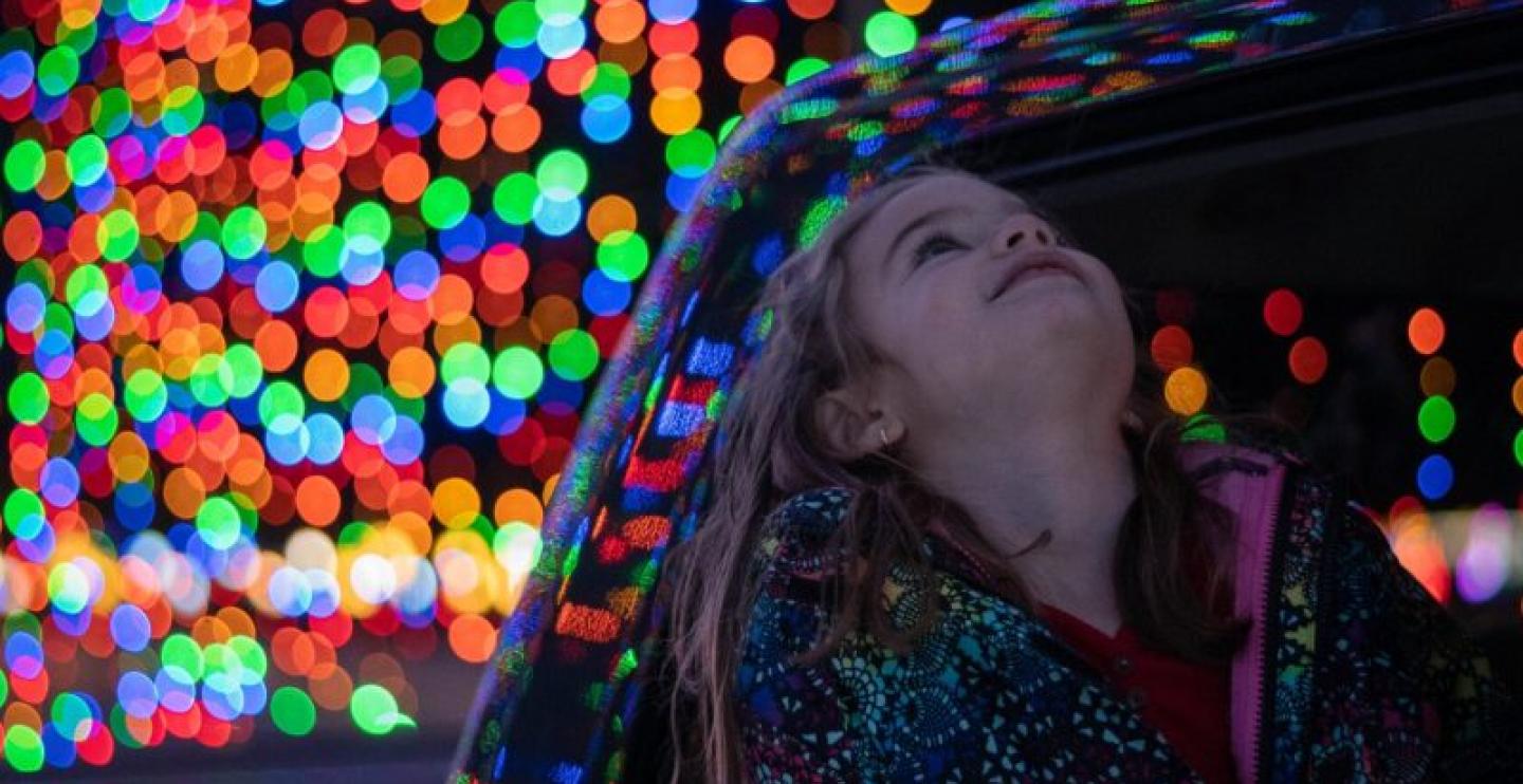 A young girl gazes up at the magical holiday light display.